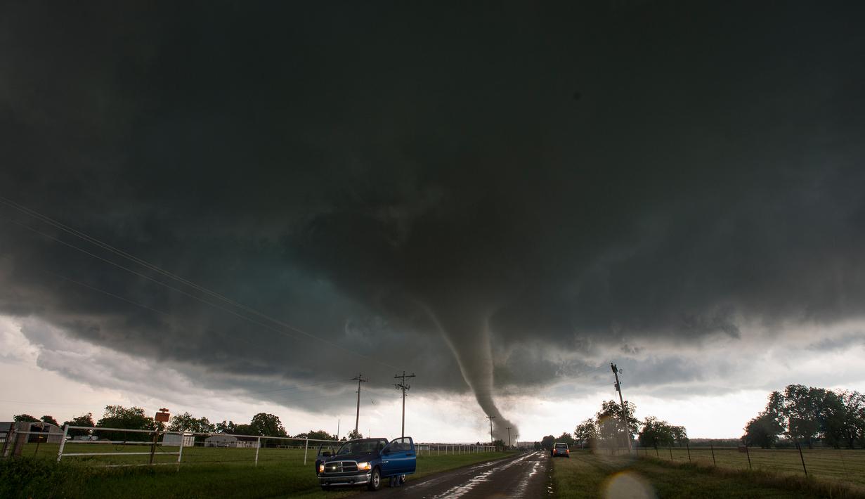 Mobil berhenti di sisi jalan ketika tornado besar melewati daerah perumahan dari selatan Wynnewood, Kota Oklahoma, Senin (9/5). Tornado tersebut mendarat dengan cepat dan menghancurkan bangunan yang dilewatinya. (Josh EDELSON/AFP)