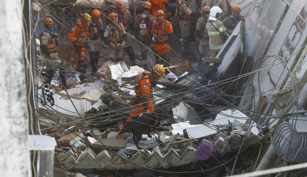 Petugas pemadam kebakaran menggunakan anjing pelacak untuk mencari kemungkinan korban selamat dari bangunan empat lantai yang runtuh semalam di kawasan kumuh Rio das Pedras, Rio de Janeiro, Brasil (3/6/2021). (AP Photo/Bruna Prado)
