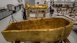 Para arkeolog merestorasi sarkofagus atau peti mati emas Firaun Tutankhamun di laboratorium restorasi Grand Egyptian Museum (GEM), Giza, Mesir, Senin (13/4/2020). Firaun Tutankhamun merupakan Raja Mesir Kuno yang memerintah antara tahun 1342-1325 SM. (Khaled DESOUKI AFP)