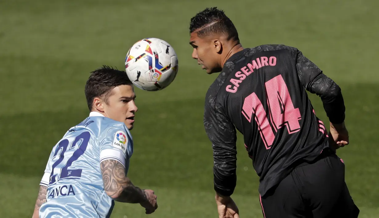 Penyerang Celta Vigo, Santi Minan bersaing dengan gelandang Real Madrid, Casemiro pada lanjutan Liga Spanyol 2020/2021 di Balaidos, Sabtu (20/3/2021). Karim Benzema jadi bintang saat Real Madrid melibas Celta Vigo 3-1. (AP Photo/Lalo R.Villar)