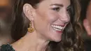 Kate Middleton, Duchess of Cambridge tersenyum selama Royal Variety Performance di Royal Albert Hall, London (18/11/2021). Kate menata rambutnya dengan ikal glamor yang jatuh ke satu sisi, meningkatkan penampilannya dengan anting-anting emas dan clutch hitam. (AFP/Justin Tallis)