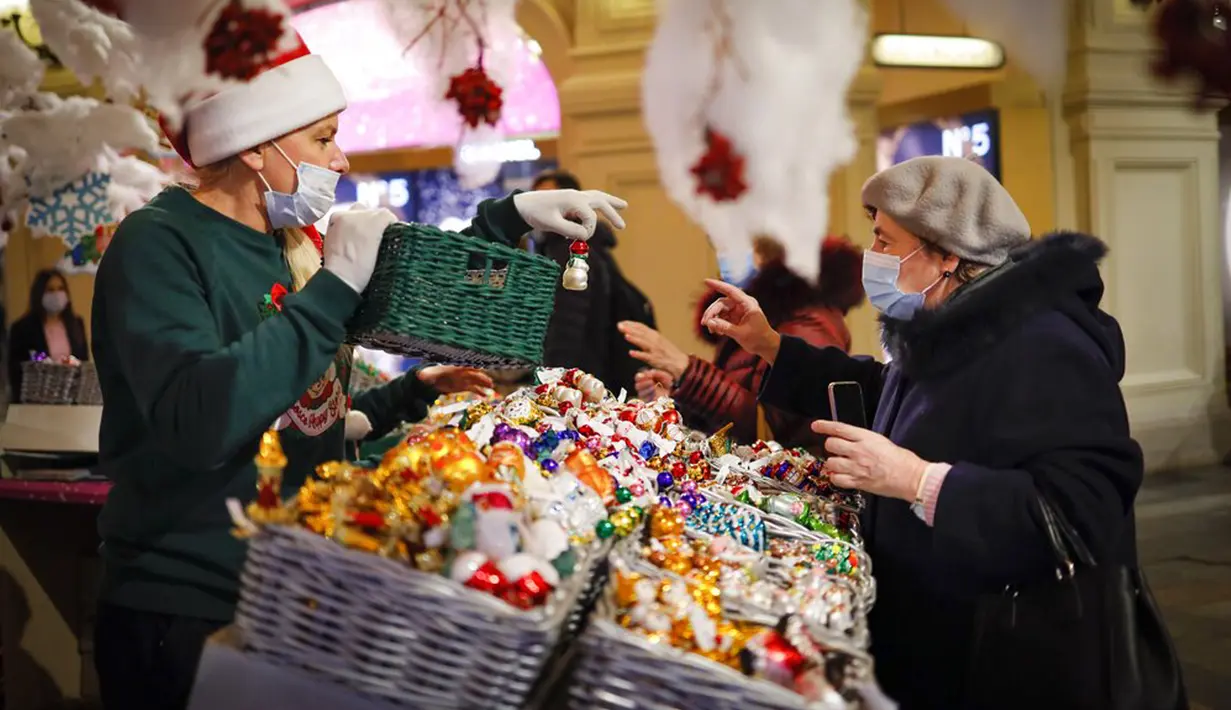 Seorang wanita yang mengenakan masker untuk membantu mengekang penyebaran virus corona COVID-19 melihat dekorasi Natal di GUM State Department Store, Moskow, Rusia, Senin (23/11/2020). Rusia saat ini memiliki jumlah kasus COVID-19 terbesar kelima di dunia. (AP Photo/Alexander Zemlianichenko)