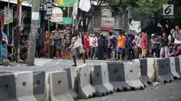Massa bertopeng menantang aparat keamanan saat terjadi bentrok di kawasan Slipi, Jakarta Barat, Rabu (22/5/2019). Polisi membalas lemparan batu para pengunjuk rasa dengan menembakkan gas air mata. (Liputan6.com/Gempur Muhammad Surya)