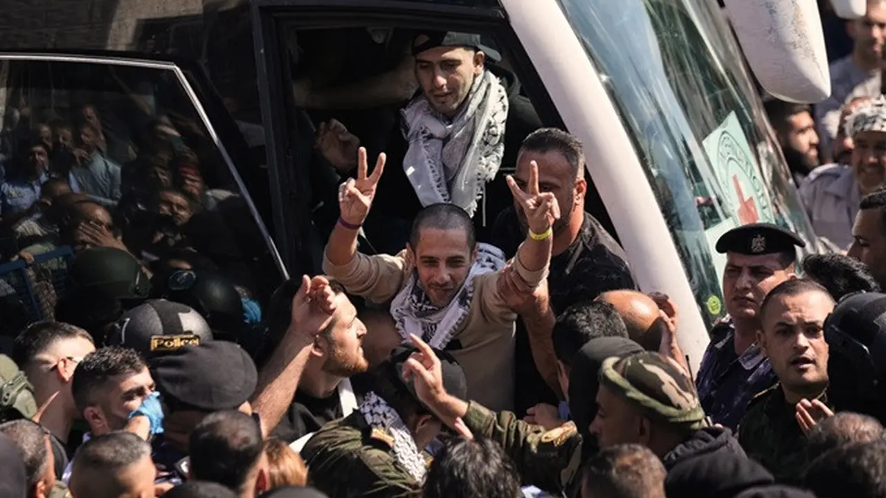 Seorang tahanan Palestina mengangkat tangan dengan tanda kemenangan saat tiba di Ramallah, Tepi Barat, setelah dibebaskan dari penjara Israel dalam kesepakatan gencatan senjata antara Israel dan Hamas, Senin (13/10/2025).