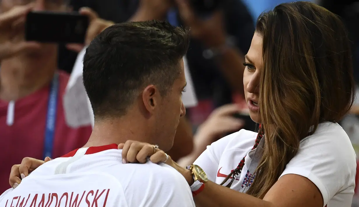 Kapten Polandia, Robert Lewandowski dihibur istrinya, Anna Lewandowska seusai dikalahkan Senegal pada pada penyisihan grup H di Piala Dunia 2018 di Stadion Spartak, Moskow, Selasa (19/6). Meski lebih diunggulkan, Polandia kalah 1-2. (FRANCK FIFE/AFP)