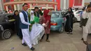 Sepasang suami istri Afghanistan meninggalkan aula pernikahan setelah upacara pernikahan massal di Kabul, Afghanistan, 13 Juni 2022. Upacara pernikahan dihadiri ratusan tamu dan pejuang Taliban yang membawa senjata. (Sahel ARMAN/AFP)