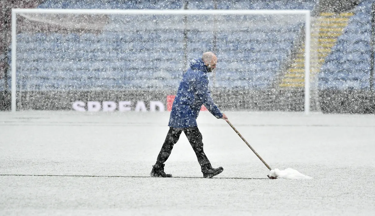 Pekerja staf membersihkan salju dari lapangan sebelum pertandingan antara Burnley dan Tottenham Hotspur di Turf Moor, Inggris, Minggu (28/11/2021). Meskipun upaya membersihkan lapangan sudah dikerahkan, laga Burnley dan Tottenham akhirnya diputuskan ditunda. (AP Photo/Rui Vieira)