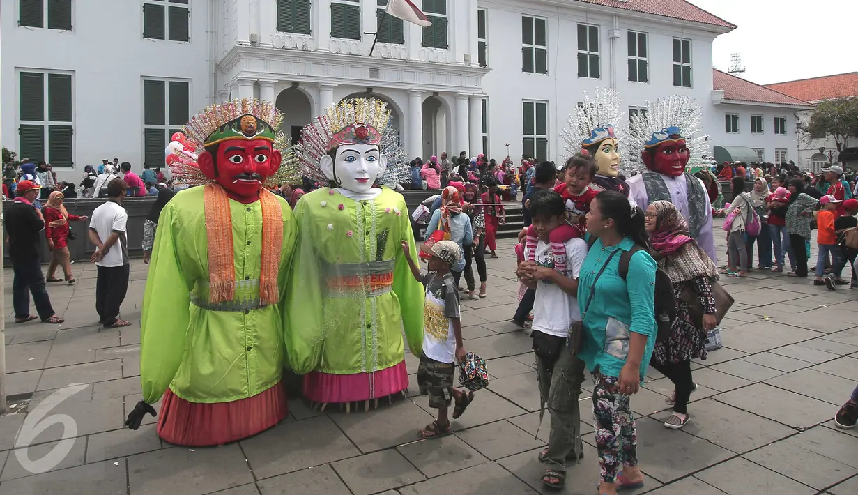 Pengunjung melihat Ondel-ondel yang dipajang di sekitar Museum Fatahillah, Jakarta, Jumat (25/12/2015). Harganya yang murah menjadikan Kota Tua tempat wisata yang digandrungi warga jakarta dan sekitarnya. (Liputan6.com/Angga Yuniar)