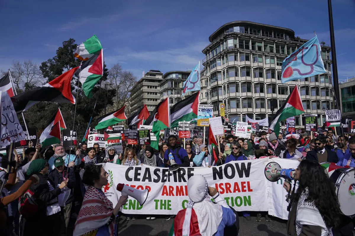 Demonstran memegang spanduk dan bendera saat mereka berkumpul menjelang pawai mendukung rakyat Palestina di Gaza, di London, pada 9 Maret 2024. (AP)