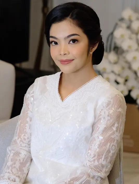 Ia tampil dibalut baju putih model v neck dengan detail bordir. Ia juga menata rambutnya bergaya sanggul dengan riasan flawlessnya.  [@jacquelinestephani]