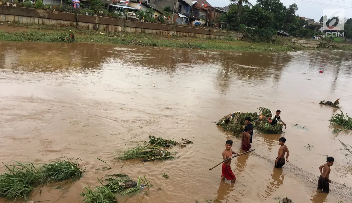 Anak-anak menaruh jaring di derasnya arus Sungai Ciliwung, Rawajati, Jakarta, Selasa (6/2). Meski sedang meluap, hal tersebut tidak menyurutkan niat anak-anak untuk beraktivitas di sekitar sungai. (Liputan6.com/Immanuel Antonius)