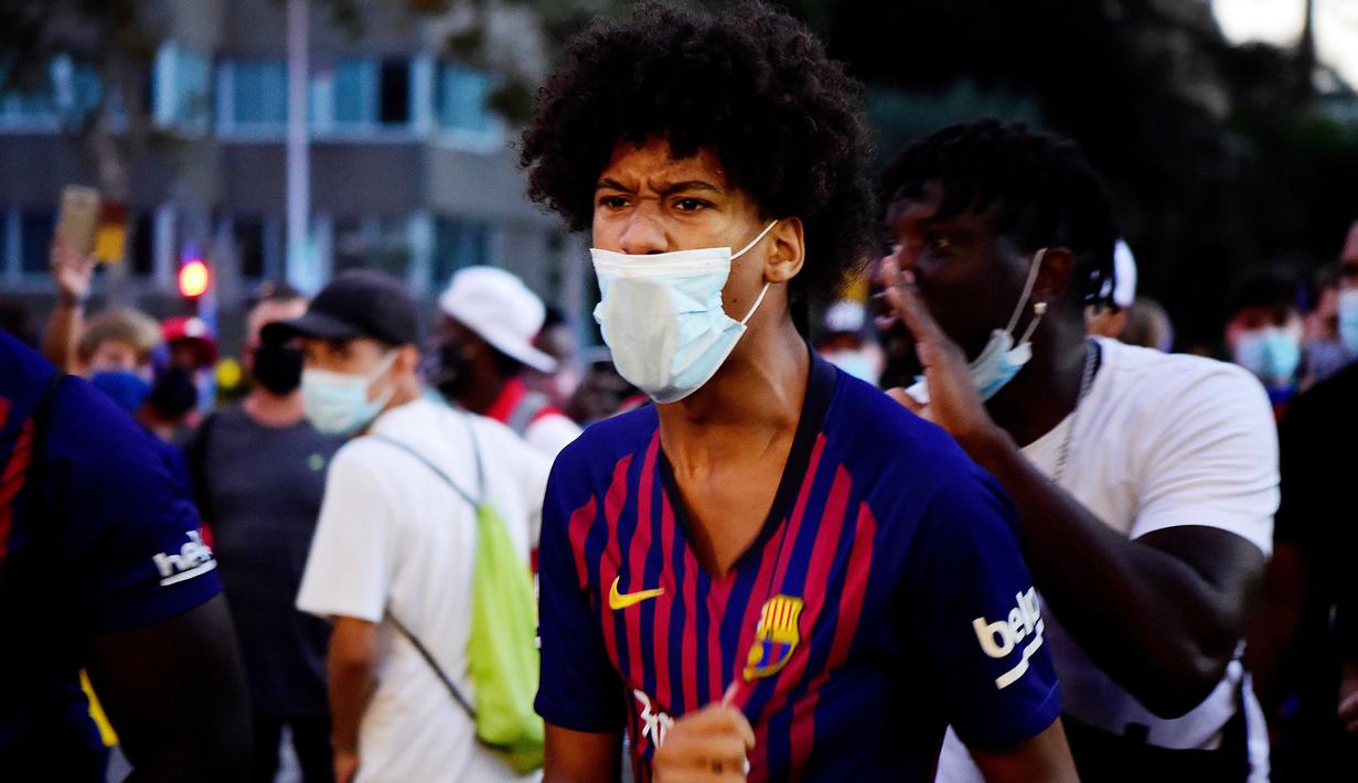 Suporter berteriak saat protes di depan kantor Barcelona, Rabu (26/8/2020). Dalam aksi tersebut fans meminta Lionel Messi bertahan dan menuntut Josep Maria Bartomeu mundur dari jabatannya. (AFP/Pau Barrena)