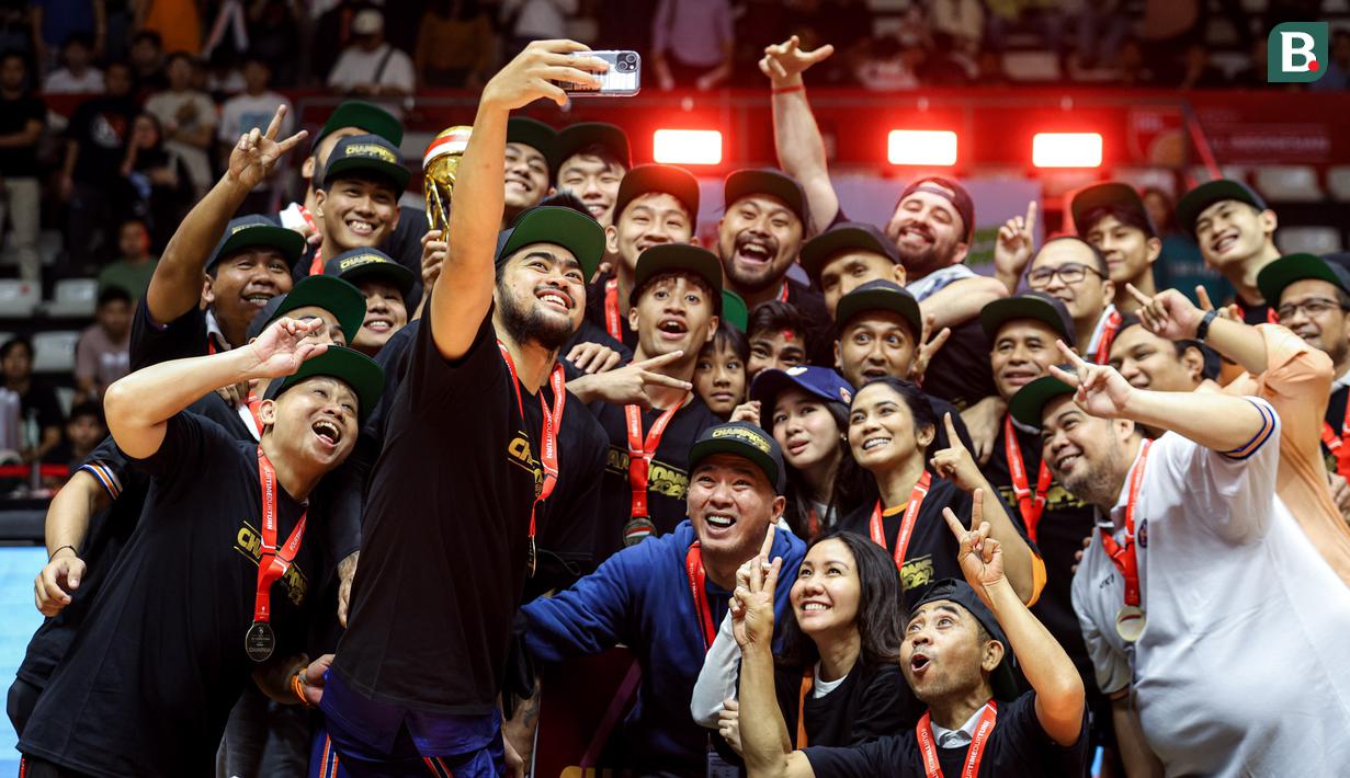 Pemain, pelatih, dan ofisial Pelita Jaya melakukan swafoto setelah merayakan kemenangan timnya atas Satria Muda dalam laga gim ketiga final IBL All Indonesia 2024 melawan Satria Muda yang berlangsung di Hall Basket, Senayan, Jakarta, Sabtu (06/10/2024). (Bola.com/Bagaskara Lazuardi)