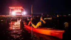 Para penonton menyaksikan penampilan band Dagamba dari atas perahu saat konser musik Laivā di Danau Juglas, Riga, Latvia, 14 Agustus 2021. Warga Latvia bisa menikmati konser musik dari atas kayak, sampan, dan kapal motor bahkan ketika mereka belum divaksin COVID-19. (Gints Ivuskans/AFP)