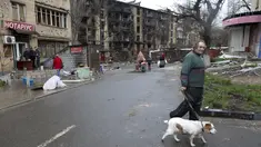 Seorang pria dengan seekor anjing berjalan di jalan yang rusak selama pertempuran sengit di gedung apartemen di daerah yang dikendalikan oleh pasukan separatis yang didukung Rusia di Mariupol, Ukraina, Selasa (19/4/2022).  (AP Photo/Alexei Alexandrov)