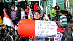 Seorang perempuan saat mengikuti aksi di depan Gedung Komisi Pemberantasan Korupsi (KPK), Jakarta, Senin (16/02/15).  Para pelajar mengayuh sepeda ontel selama 13 hari dari  Jember menuju Jakarta untuk mendukung KPK. (Liputan6.com/Faisal R Syam)