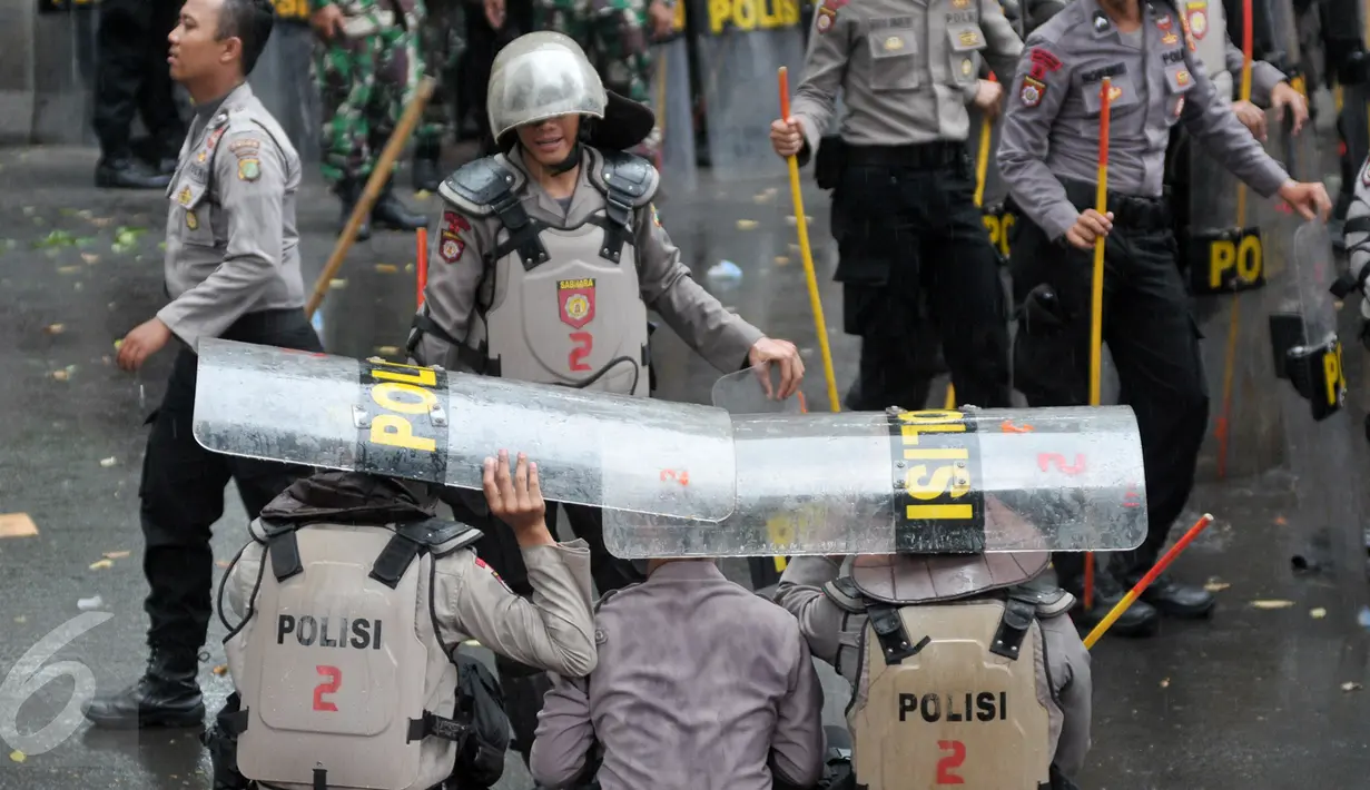 Hujan yang mengguyur di Ibukota tidak menyurutkan petugas kepolisian untuk tetap menjaga aksi Hari Buruh di Jalan Medan Merdeka, Jakarta, Senin (1/5). (Liputan6.com/ Yoppy Renato)
