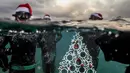 Penyelam berpose saat akan menempatkan pohon Natal di dasar laut lepas pantai Tripoli, Lebanon, Selasa (18/12). Hal ini dilakukan untuk menyambut Natal. (IBRAHIM CHALHOUB/AFP)