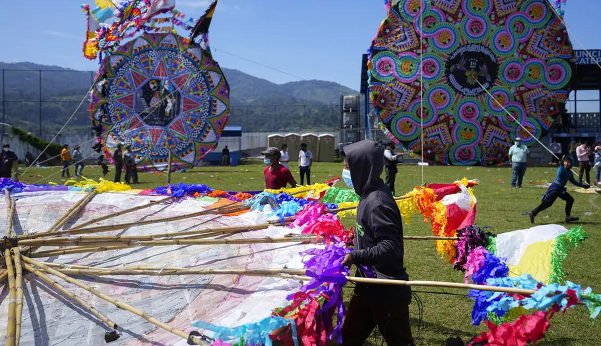 Seorang pria membantu membawa layang-layang besar untuk ditampilkan pada Hari Semua Orang Kudus sebagai bagian dari perayaan Hari Kematian di Santiago Sacatepequez, Guatemala, 1 November 2021. Perayaan digelar dengan sejumlah pembatasan untuk mengekang penyebaran COVID-19. (AP Photo/Moises Castillo)
