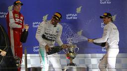 Lewis Hamilton (tengah) menyemprotkan sampanye kea rah peringkat tiga, Nico Rosberg (kanan), dan Kimi Raikkonen dari Ferrari. (photo by AFP/MARWAN NAAMANI)