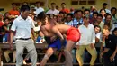 Dua pria bertarung gulat Khmer selama festival Pchum Ben atau festival kematian di desa Vihear Suor, provinsi Kandal (9/10). Warga Kamboja turun dari desa kecil di timur laut ibu kota untuk menyaksikan pertarungan ini. (AFP Photo/Tang Chhin Sothy)