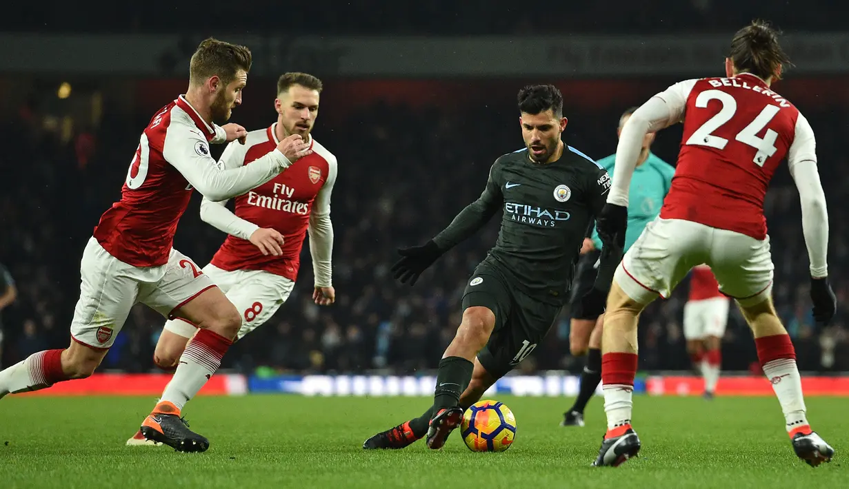 Striker Manchester City, Sergio Aguero dikepung pemain Arsenal Shkodran Mustafi, Welsh Aaron Ramsey dan Hector Bellerin pada laga pekan ke-28 Premier League di Emirates Stadium,  Jumat (2/3). Manchester City mempermalukan Arsenal 3-0. (Glyn KIRK/AFP)