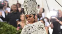 Penyanyi Rihanna berpose untuk fofotgrafer setibanya pada pagelaran Met Gala 2018 di Museum Seni Metropolitan New York, Senin (7/5). Menyempurnakan gayanya, aksesori di kepalanya yang menyerupai mitre atau mitra. (Evan Agostini/Invision/AP)