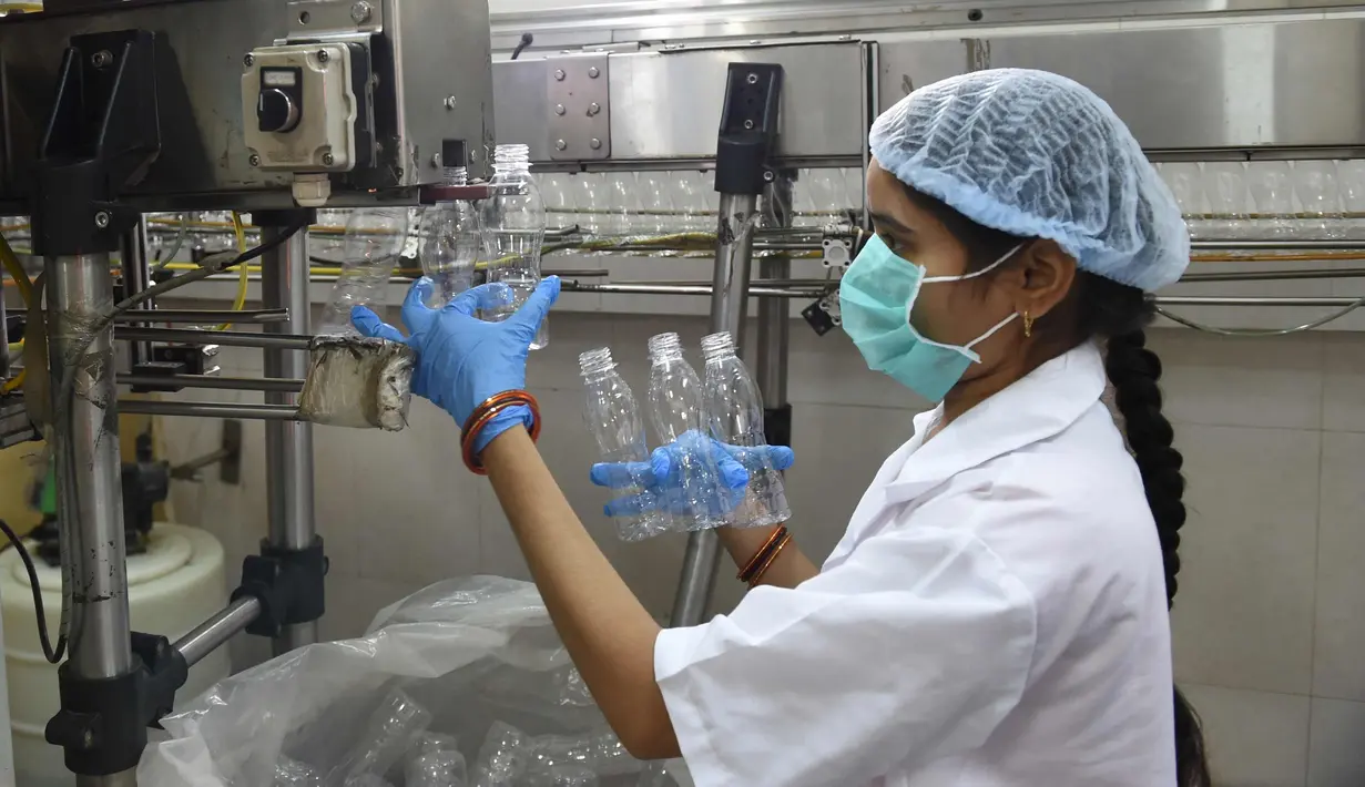 Pekerja mengecek botol di pabrik air mineral alami Aava di Ahmedabad, India (19/3). Hari Air Sedunia jatuh pada tanggal 22 Maret dan berfokus pada pentingnya akses universal terhadap air bersih, sanitasi dan fasilitas kebersihan. (AFP Photo/Sam Panthaky)