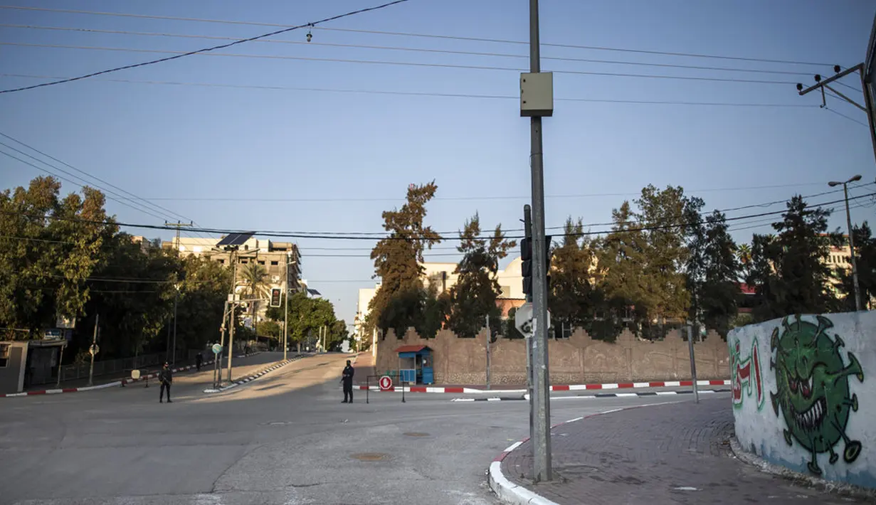 Polisi Hamas berjaga di jalanan yang kosong selama lockdown untuk menahan pandemi virus corona COVID-19 di Jalur Gaza, Palestina, Jumat (18/12/2020). Jam malam juga memaksa warga Gaza untuk tetap berada di rumah. (AP Photo/Khalil Hamra)