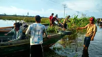 Warga menggunakan perahu untuk menyeberangi Jalan Trans-Kalimantan yang banjir. (Liputan6.com/Rajana K)