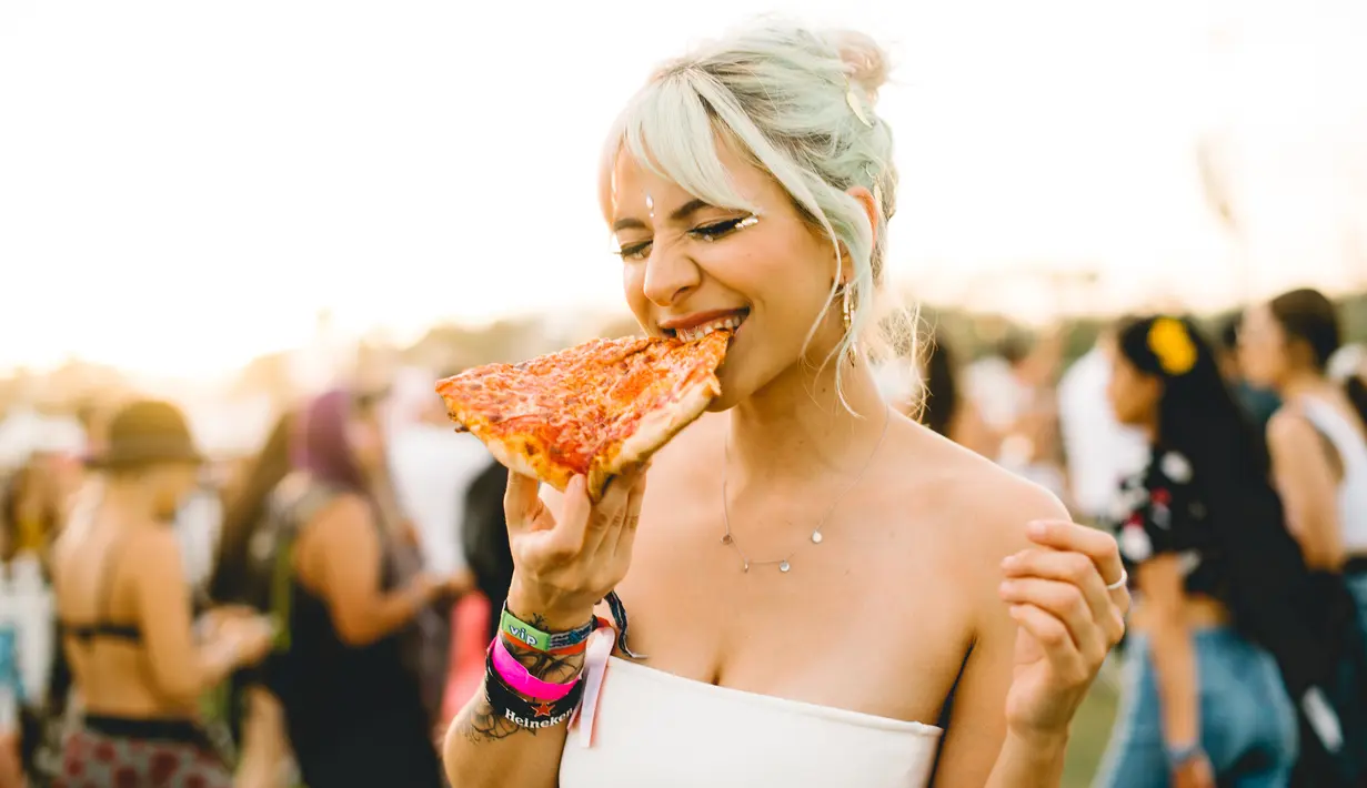 Pengunjung wanita menikmati pizza selama Coachella Music & Arts Festival 2019 di Indio, California (15/4). Festival Coachella ini sudah ada sejak tahun 1999. (AFP Photo/Matt Winkelmeyer)