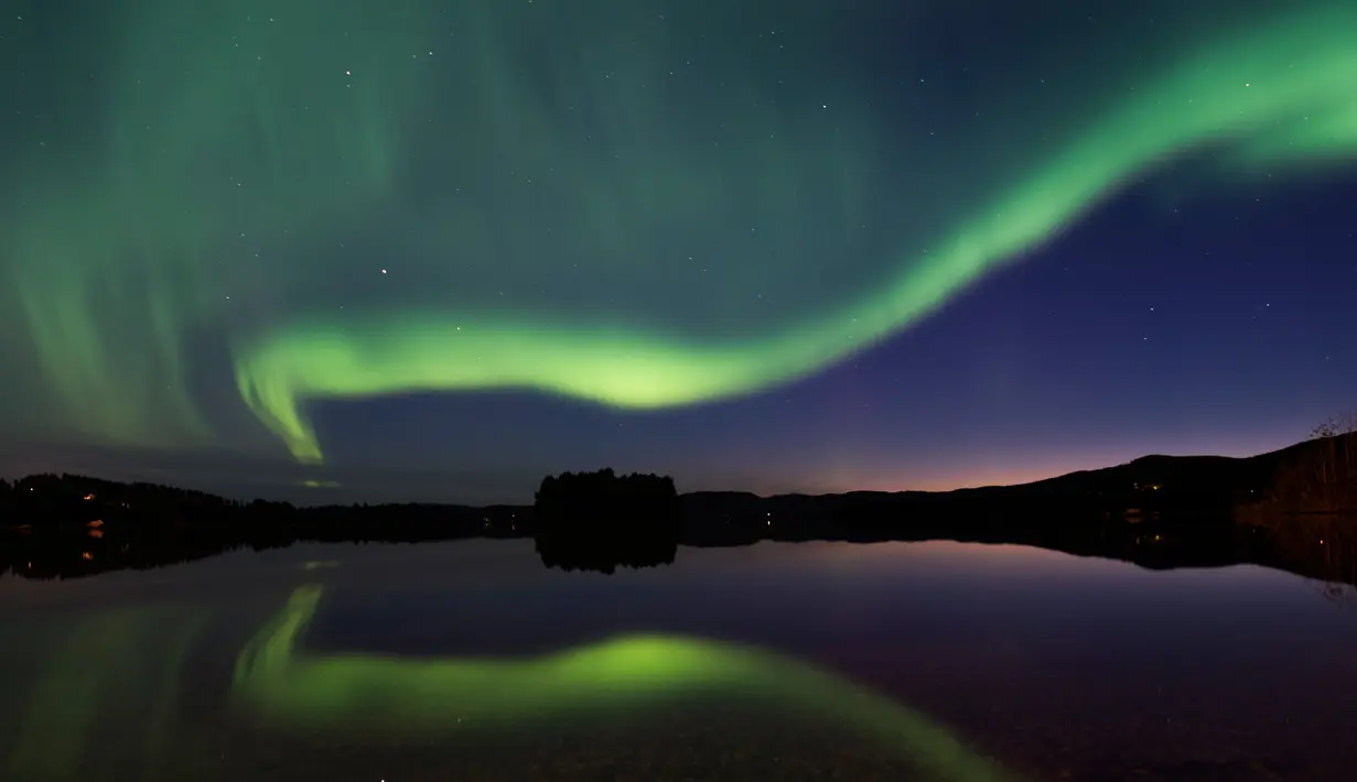 Cahaya aurora borealis menerangi langit malam Desa Erikslund di Vasternorrland County, Swedia (23/8). Fenomena alam yang indah ini terjadi pada bulan Maret-April dan September-Oktober. (AFP PHOTO/ JONATHAN NACKSTRAND)