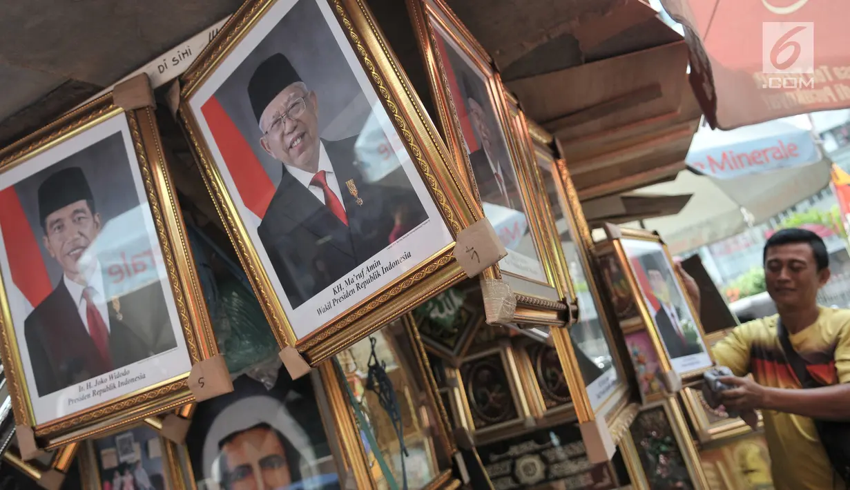 Pedagang merapikan foto Presiden-Wapres 2019-2024, Joko Widodo-KH Ma'ruf Amin di salah satu toko di Pasar Baru, Jakarta, Senin (26/8/2019). Foto Presiden dan Wapres Terpilih dijual Rp 200 ribu hingga Rp 900 ribu per paket (foto presiden dan wakil presiden). (merdeka.com/Iqbal S. Nugroho)