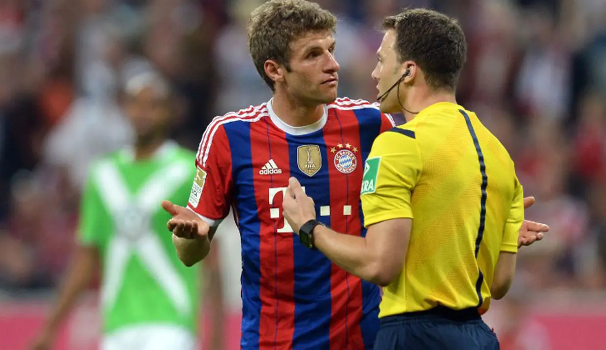 Gelandang Bayern Munich, Thomas Mueller (kiri), melakukan protes kepada wasit Felix Zwayer, saat berlaga melawan VfL Wolfsburg dilanjutan Bundesliga di Allianz Arena, (23/8/2014). (AFP PHOTO/Christof Stache)