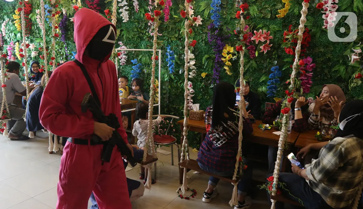 Pramusaji menggunakan kostum serial Netflix Squid Game di Cafe Strawberry, Jakarta, Sabtu (16/10/2021). Cafe tersebut melakukan inovasi dengan mengusung tema permainan yang ada dalam film asal Korea Selatan yakni Squid Game untuk memberikan daya tarik bagi pengunjung. (Liputan6.com/Herman Zakharia)