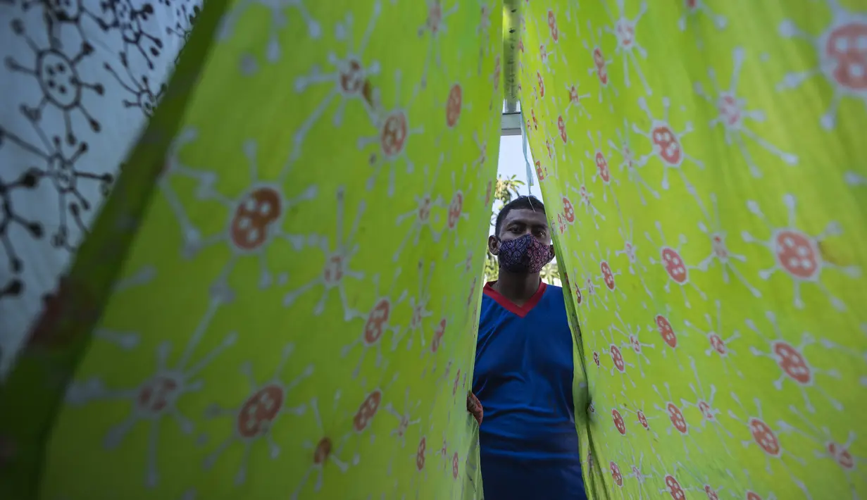 Penyandang disabilitas menjemur kain batik dengan motif virus corona di Surabaya, Jawa Timur (19/8/2020). Di tengah pandemi Covid-19, sekelompok penyandang disabilitas di Surabaya membuat batik bermotifkan virus corona. (AFP/JUNI KRISWANTO)