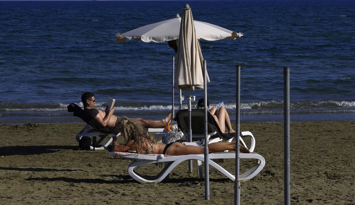 Orang-orang menikmati cuaca hangat di pantai Makenzi di kota selatan Larnaca, Siprus, Senin (8/11/2021). Cuaca hangat tersebut membuat banyak orang untuk mencapai Mediterania timur pantai negara kepulauan. (AP Photo/Petros Karadjias)