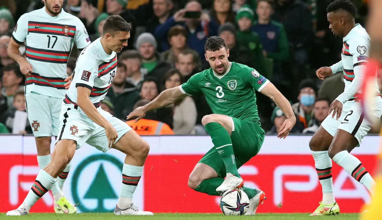 Pemain Portugal Joao Palhinha (kedua kiri) dan Nelson Semedo (kanan) bersaing dengan bek Irlandia Enda Stevens pada laga Grup A Kualifikasi Piala Dunia 2022 Zona Eropa di Stadion Aviva, Jumat (12/11/2021) dinihari WIB. Diwarnai kartu merah Pepe, Portugal ditahan imbang Irlandia 0-0. (Paul Faith/AFP)