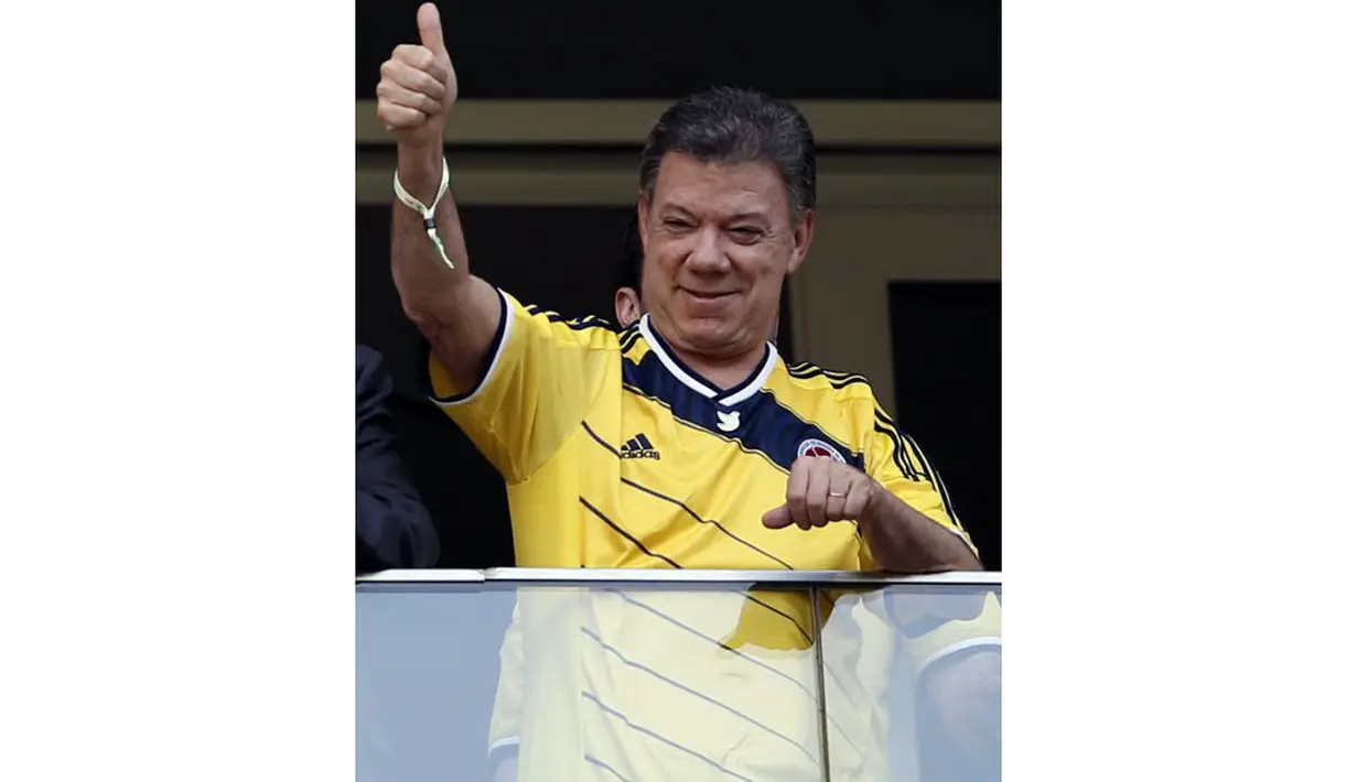 Presiden Kolombia, Juan Manuel Santos, memberikan acungan jempol buat kedua tim yang berlaga di babak penyisihan Piala Dunia 2014 Grup C di Stadion National Mane Garrincha, Brasil, (19/6/2014).(AFP PHOTO/Adrian Dennis)