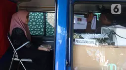 Seorang warga melakukan proses administrasi perubahan nama jalan pada KTP elektronik di Halaman Masjid Al Hikmah Hidayah, Cipayung, Jakarta Timur, Rabu (29/6/2022). Pemprov DKI Jakarta menggelar pelayanan jemput bola di enam wilayah terkait perubahan data administrasi kependudukan imbas pergantian 22 nama jalan menggunakan nama tokoh Betawi. (Liputan6.com/Herman Zakharia)