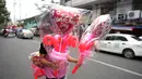Seorang pria membawa balon berbentuk hati di pasar bunga di Manila, Filipina, Senin (13/2/2023). Harga bunga naik karena tingginya permintaan sehari sebelum Hari Valentine. (AP Photo/Aaron Favila)
