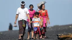 Sebuah keluarga tiba untuk menjalani prosesi menyucikan diri saat Hari Banyu Pinaruh di pantai Keramas, Gianyar, Bali, Minggu (12/5/2019). Banyu Pinaruh adalah tradisi Bali yang diadakan sehari setelah merayakan Hari Suci Saraswati untuk membersihkan jiwa dan raga. (SONNY TUMBELAKA/AFP)