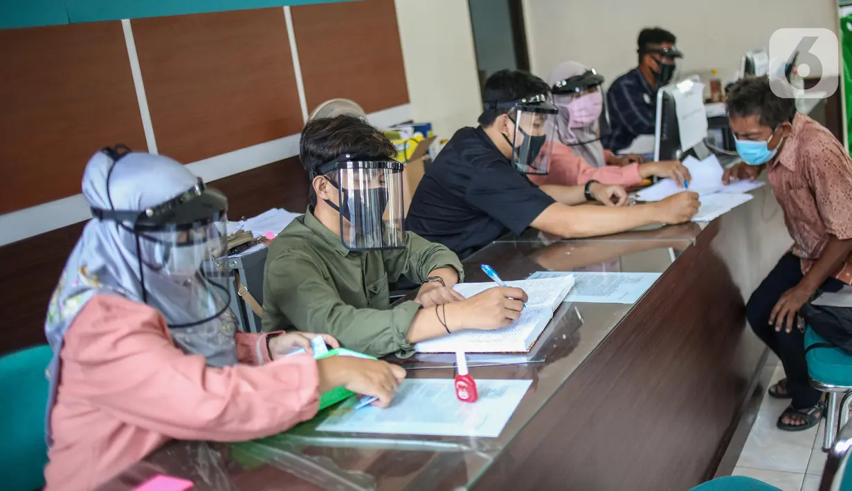 Petugas menggunakan face shield saat melayani masyarakat Dinas Kependudukan Kecamatan Pamulang, Tangerang Selatan, Jumat (29/5/2020).  Penggunaan Face Shield tersebut sebagai salah satu upaya untuk melindungi diri dalam penyebaran COVID-19. (Liputan6.com/Faizal Fanani)