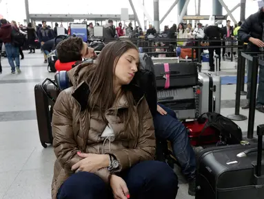 Penumpang maskapai Avianca menunggu penerbangan yang tertunda di Bandara Internasional John F Kennedy (JFK), New York, Senin (8/1). Banjir yang disebabkan kerusakan saluran air mengakibatkan kekacauan dan pembatalan sejumlah penerbangan. (AP/Richard Drew)