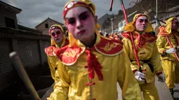 Sejumlah orang mengenakan kostum dan berdandan berjalan bersiap menguikuti festival She Huo di Longxian, provinsi Shaanxi, Tiongkok (27/2). Mereka berdandan dan mengenakan kostum yang mewakili tokoh legandaris setempat. (AFP Photo/Fred Dufour)