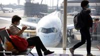 Para pelancong yang mengenakan masker menunggu penerbangan mereka di Bandara Internasional Hong Kong di Hong Kong, Selasa (21/1/2020). Masker terjual habis dan pemeriksaan suhu di bandara dan stasiun kereta api menjadi norma baru di China menyusul merebaknya wabah virus corona.  (AP/Ng Han Guan)