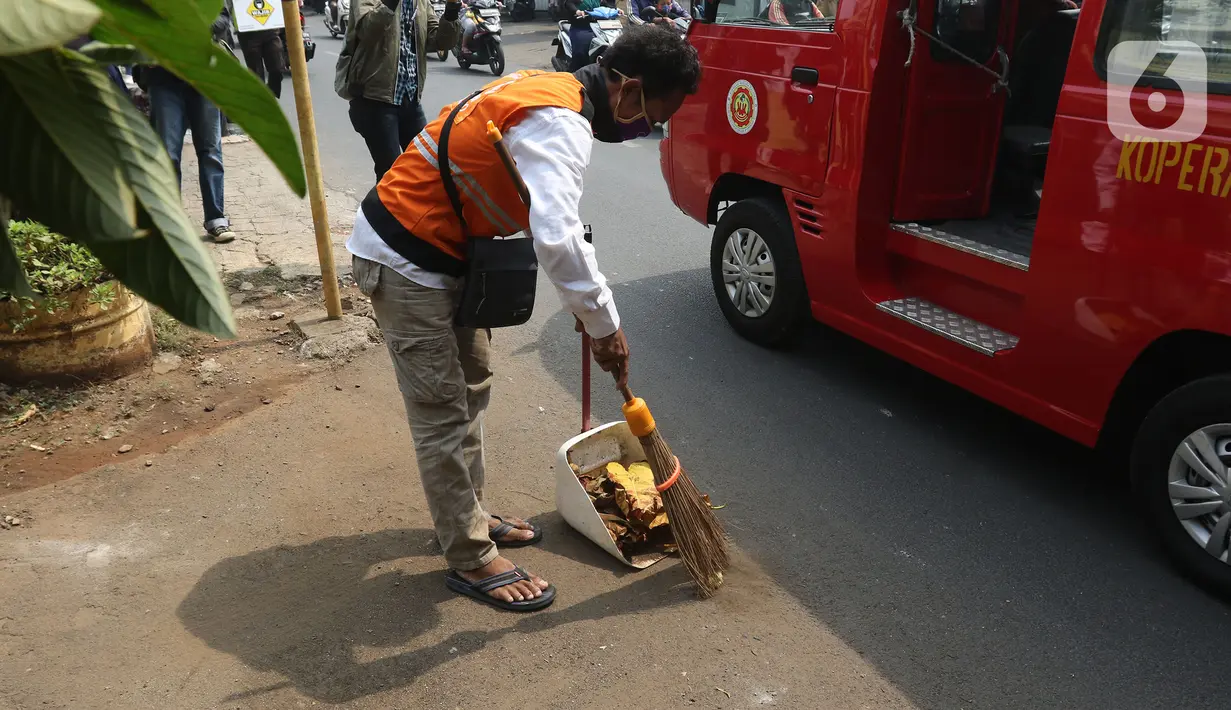Pelanggar PSSB dihukum menyapu jalanan di Kawasan Kalisari, Pasar Rebo, Jakarta Timur, Kamis (3/9/2020). Warga Kelurahan Pasar Rebo yang kedapatan keluar rumah tanpa menggunakan masker diberikan pilihan hukuman, salah satunya dimasukkan ke dalam peti mati selama 1 menit. (Liputan6.com/Herman Zakhari