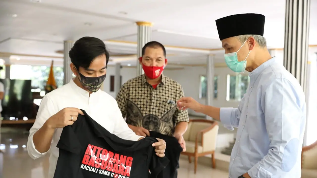 Gibran menyerahkan kaos kepada Ganjar Pranowo. (Foto: Liputan6.com/Felek Wahyu)