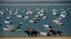 Peserta memacu kudanya saat mengikuti lomba pacuan kuda pantai tahunan di Sanlucar de Barrameda, dekat Cadiz, Spanyol (17/8). Pacuan kuda ini bermula dari para nelayan yang berlomba mengangkut tangkapan mereka melalui pantai. (AFP Photo/Cristina Quicler)