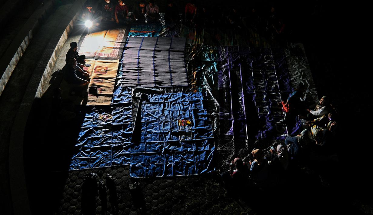 Sejumlah warga menghadiri upacara doa pada malam peringatan 17 tahun tsunami Boxing Day 2004 di monumen Kapal Tsunami Lampulo di Banda Aceh (25/12/2021). (AFP/Chaideer Mahyuddin)